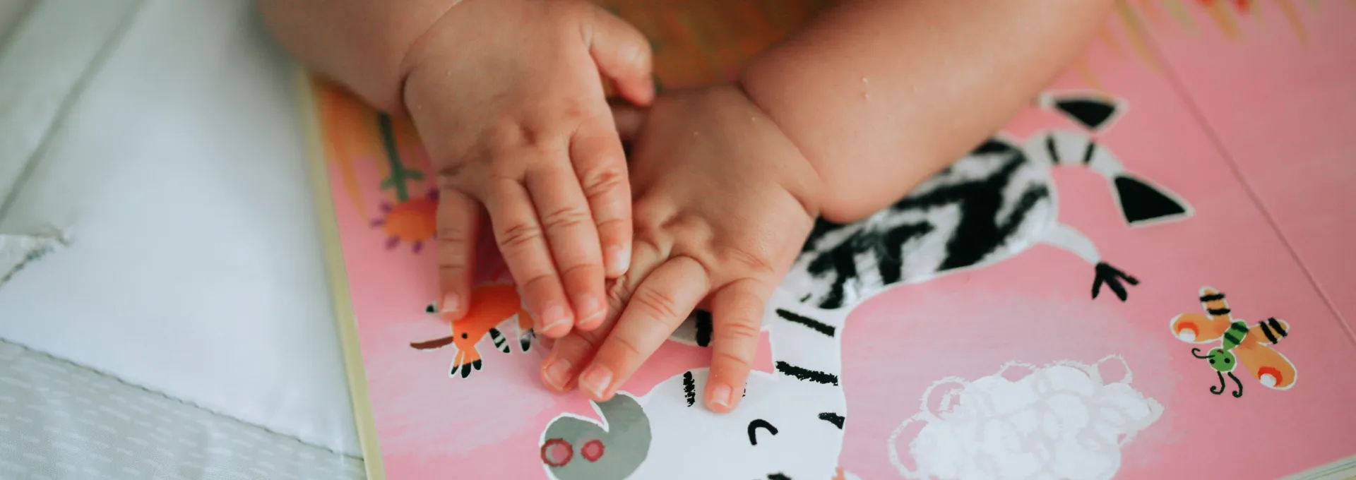 Neonato sdraiato a pancia in giù che sta guardando un libro sensoriale di immagini tattili e colorate