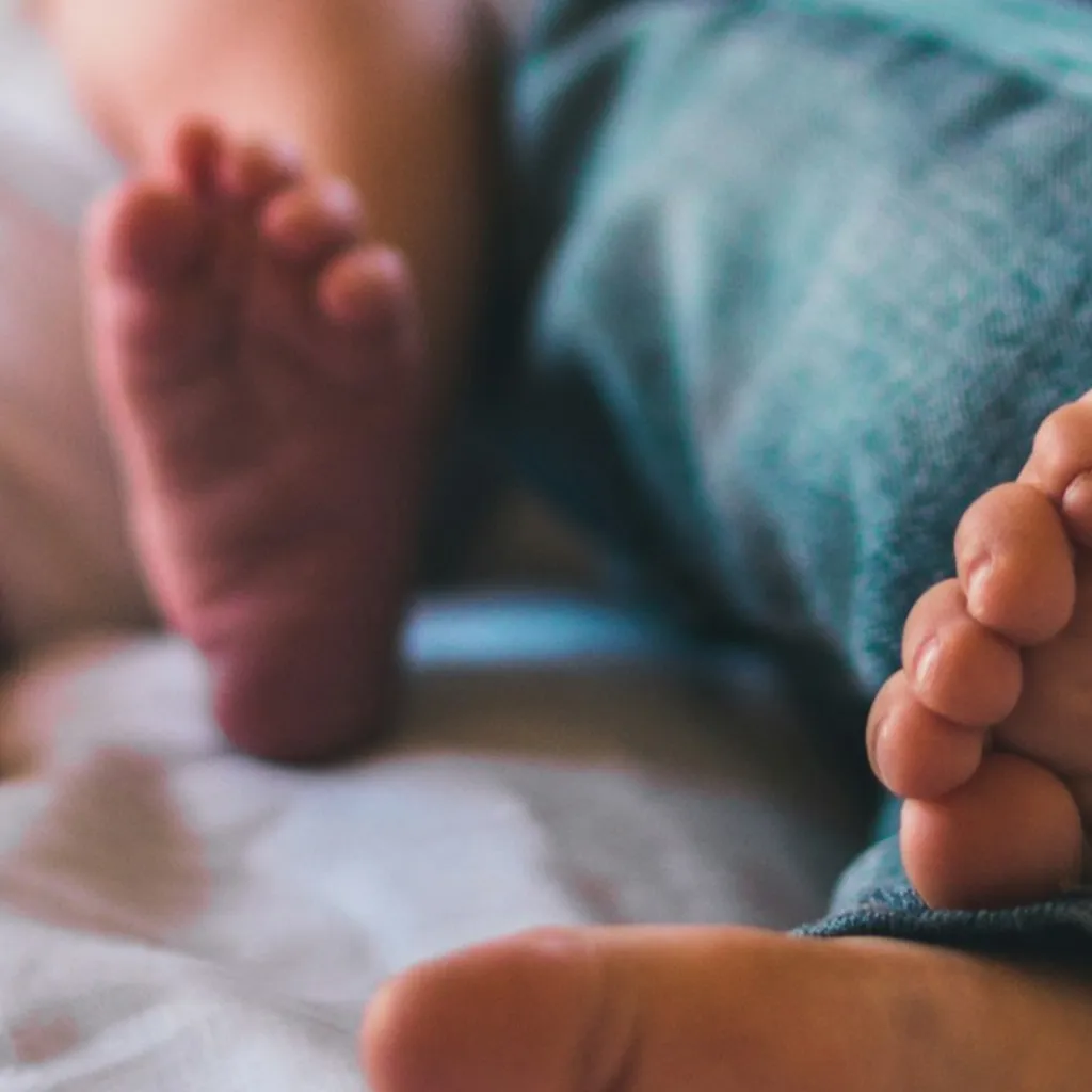 piedi di un neonato e il fratellino sdraiati insieme a letto