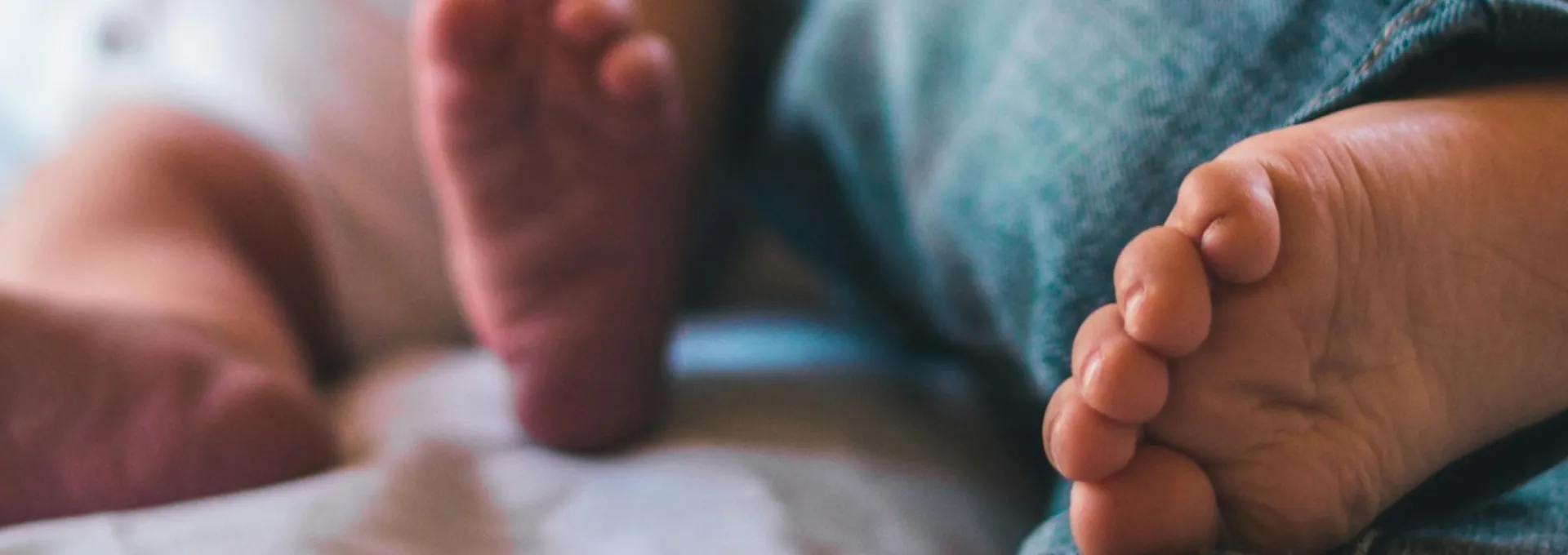 piedi di un neonato e il fratellino sdraiati insieme a letto